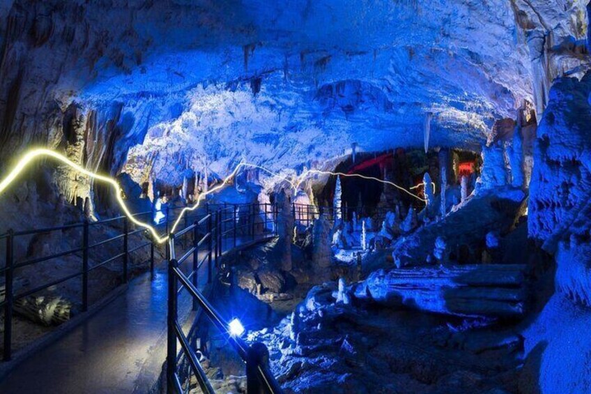 Una cueva con estalactitas y estalagmitas, iluminada con luces azules. 3