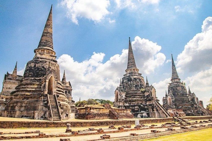 Ancient stone structures with pointed spires, likely temples, set against a clear sky. 3