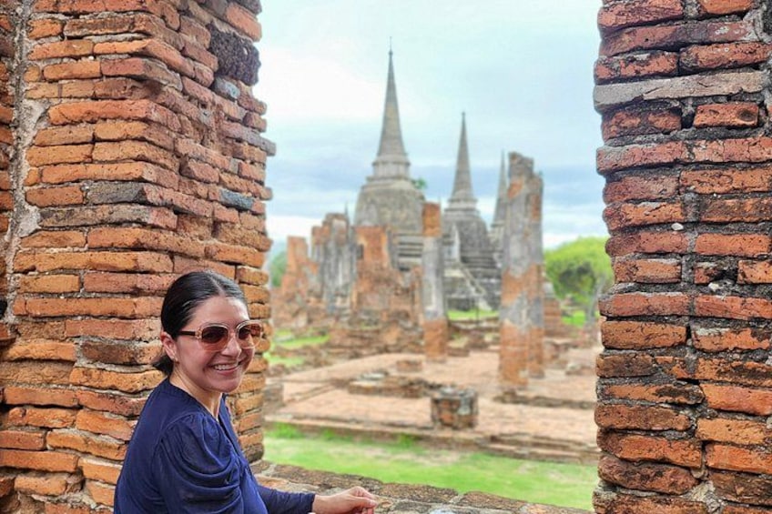 A person standing between brick walls with ancient temple ruins in the background. 2