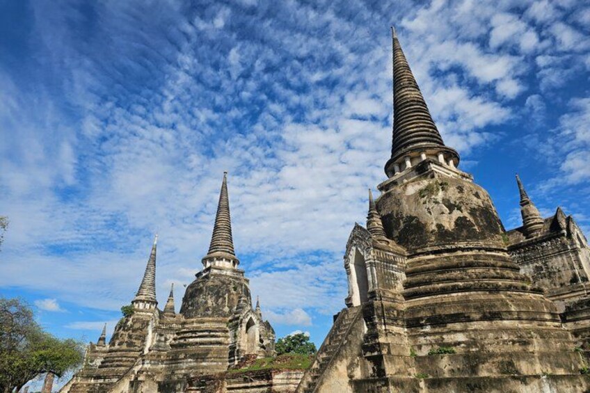 Ancient stone structures with pointed spires against a blue sky with clouds. 2