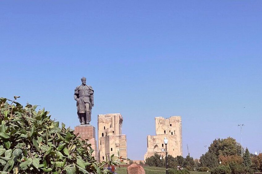 A statue, a tower, and a building in a park. 4