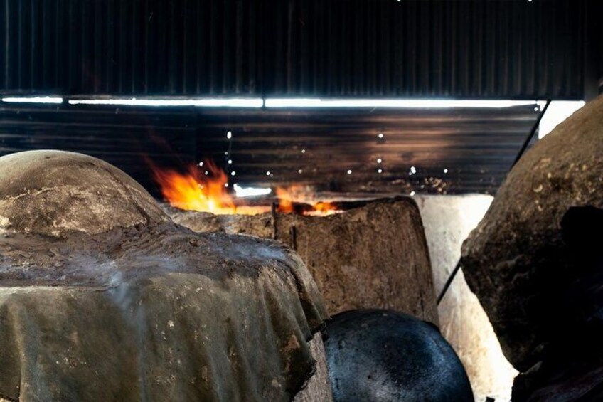 A large industrial furnace with flames and covered objects inside. 3