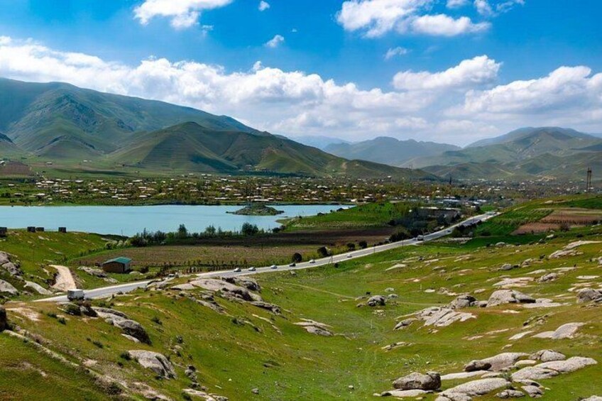 A mountainous landscape with a lake, a road, and scattered buildings. 3