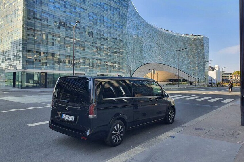 En sort varevogn parkeret på en gade med en moderne glasbygning i baggrunden. 3