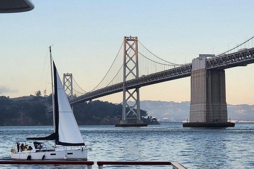 A sailboat on the water with a large suspension bridge in the background. 4