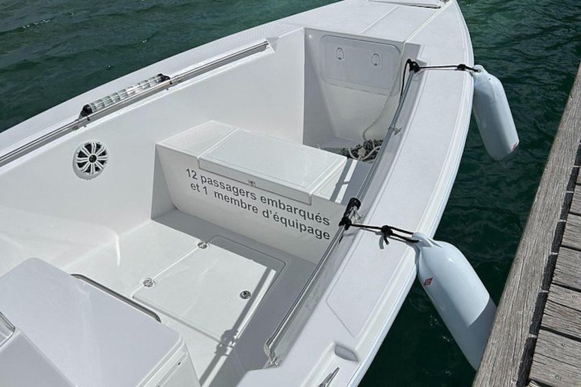 A white boat docked at a wooden pier with a sign indicating it can carry 12 passengers and 1 crew member. 4