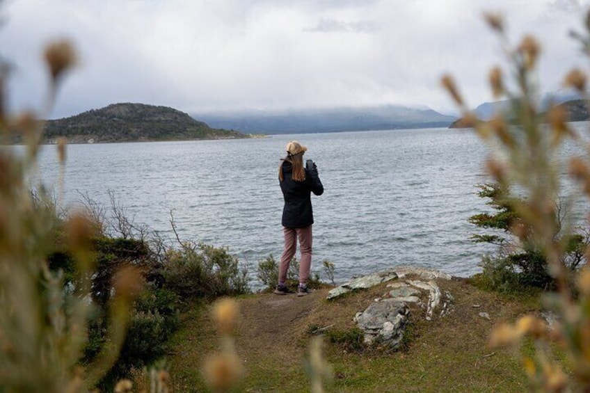 A person standing by a lake, taking a photo. 1