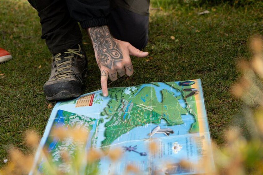 A person pointing at a map on the grass. 3