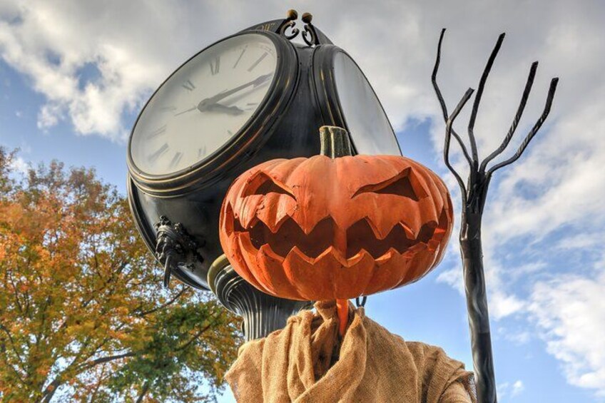 A clock with a carved pumpkin and a witch's hat. 1