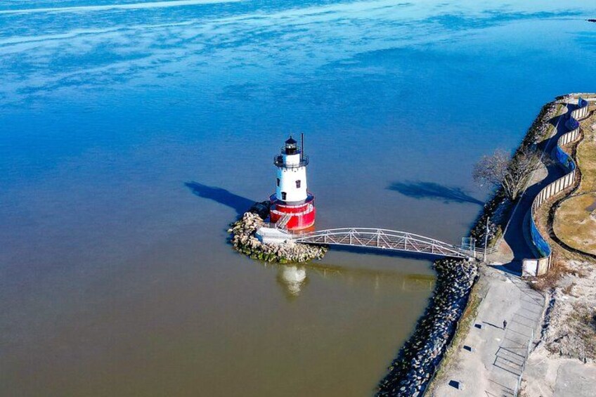 A lighthouse on a small island with a bridge connecting it to the mainland. 2