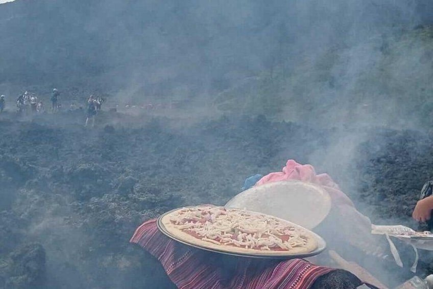 Une pizza sur une table recouverte d’une nappe, entourée de fumée, avec des personnes à l’arrière-plan. 3