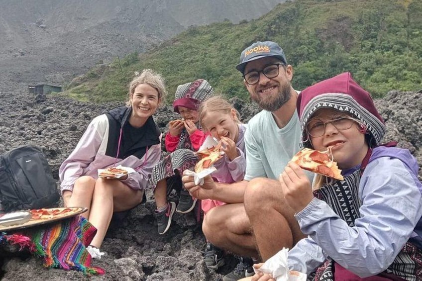 Un groupe de personnes est assis sur une surface rocheuse et mange de la pizza. 1
