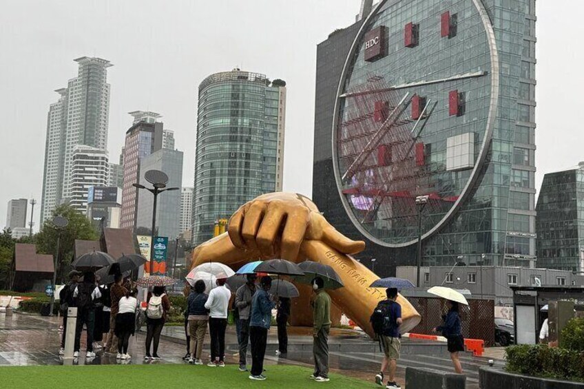 Una gran escultura de mano en un entorno urbano, con edificios altos al fondo. 4