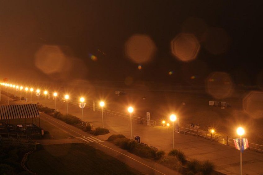 A nighttime scene with a series of streetlights lining a road, a pedestrian crossing, and a flagpole with an American flag. 2