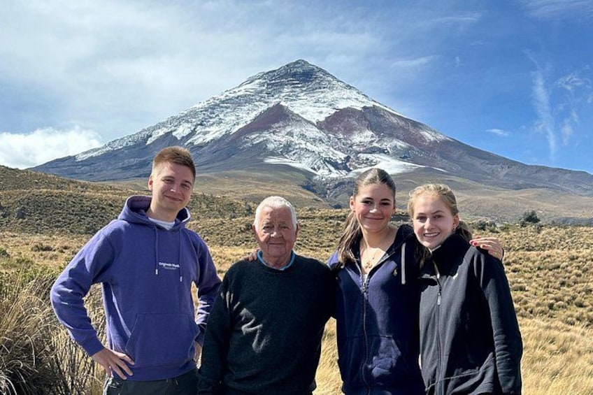 A group of people standing in a grassy field with a snow-capped mountain in the background. 5