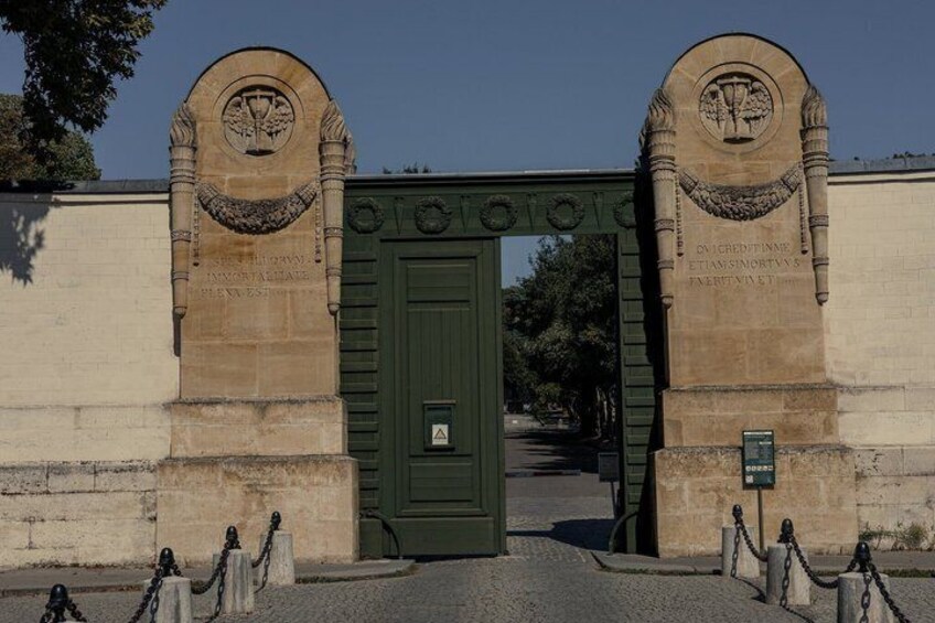 A stone archway with a green door, flanked by two stone pillars with inscriptions. 2