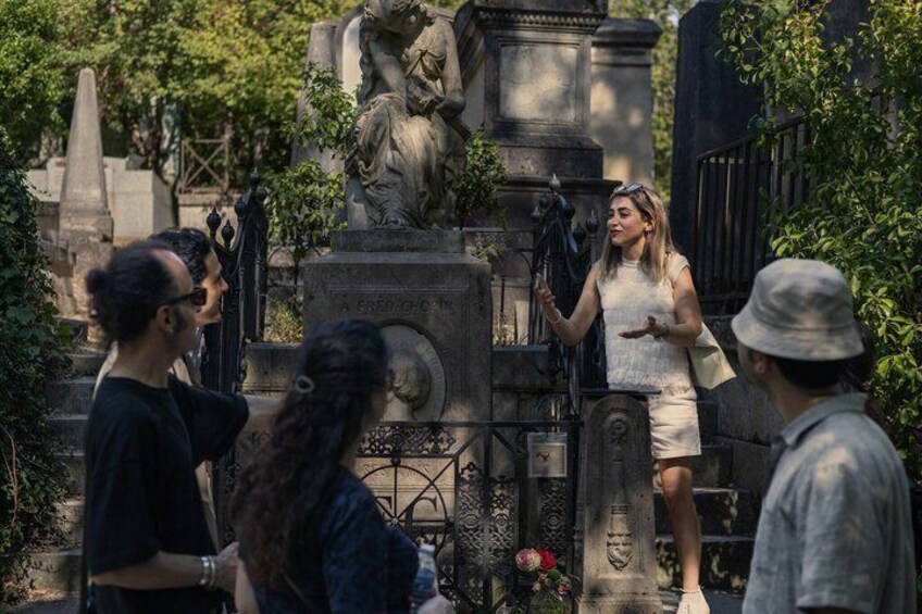 A group of people standing around a statue in a cemetery. 1