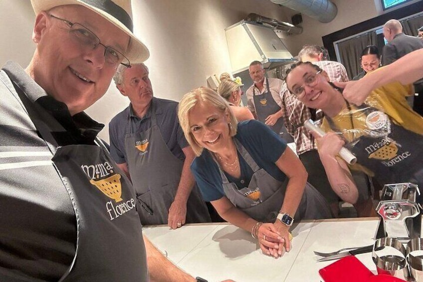 Eine Gruppe von Personen in einer Küche, bekleidet mit Schürzen mit Logos, bereitet Essen zu. 2