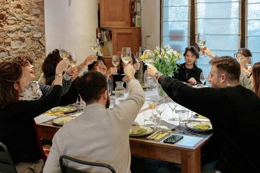 Eine Gruppe von Personen sticht mit Weingläsern an einem Esstisch in einem Restaurant an. 5