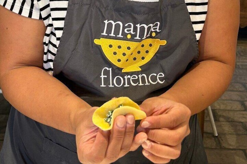 Eine Person mit einer 'Mama Florence'-Schürze, die ein Stofftier hält. 4