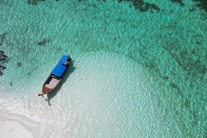 A boat on a clear turquoise sea with a sandy beach. 3