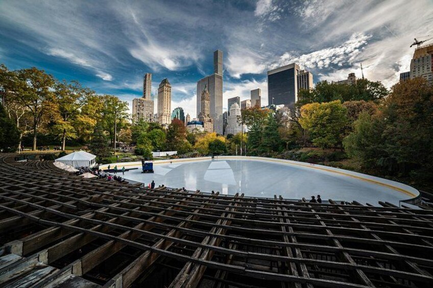 An outdoor amphitheater with a city skyline in the background. 3