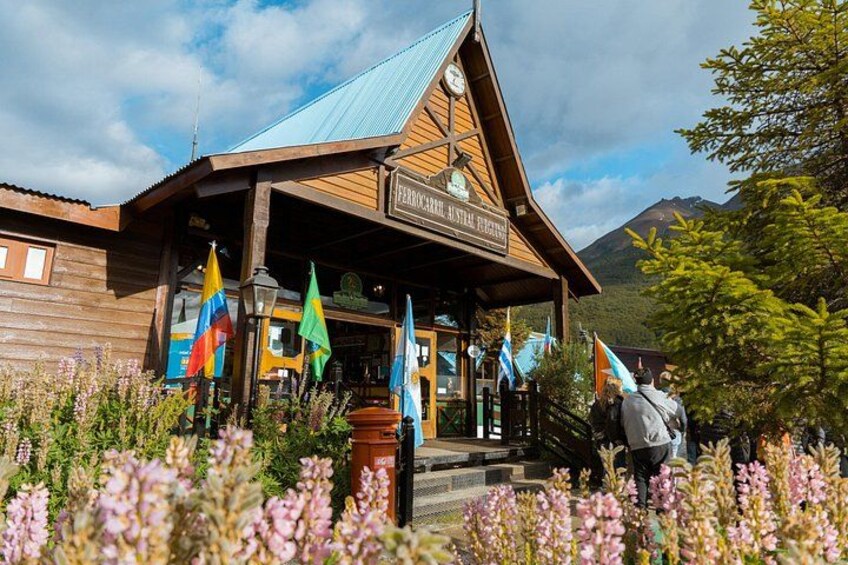 Un edificio in legno con un cartello, circondato da bandiere colorate e fiori. 2
