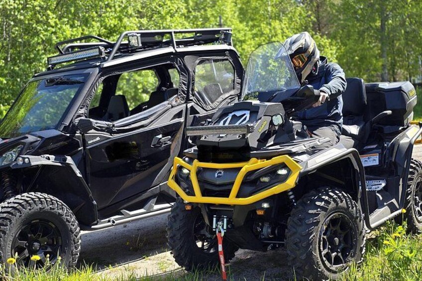 A black and yellow ATV with a rider in a helmet, parked on grass with trees in the background. 5