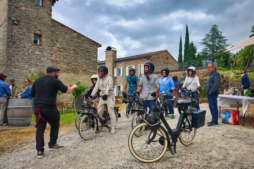 A group of people on bicycles in an outdoor setting with stone buildings in the background. 1