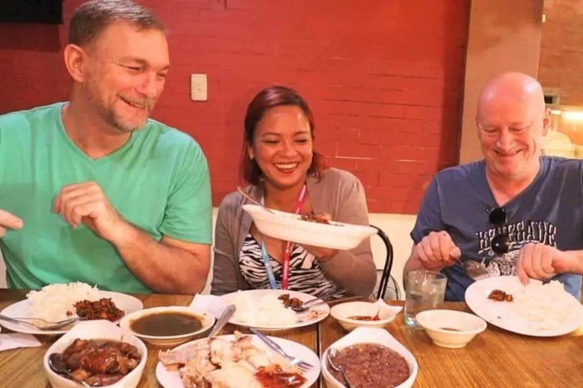 Three people sitting at a table with various dishes. 3