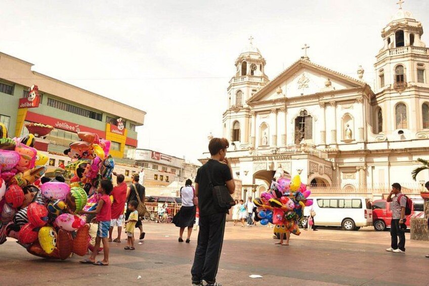 A street market with colorful balloons and a historic church in the background. 1