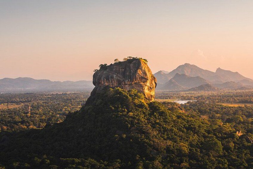 A mountain with a prominent peak, surrounded by dense forest and distant mountains. 1