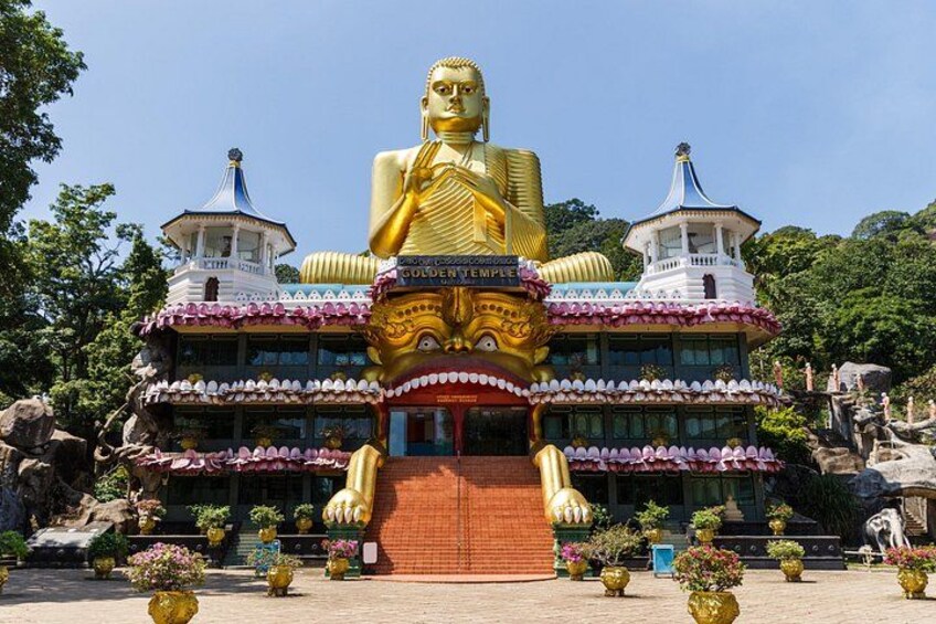 A large golden Buddha statue in front of a temple with two pagodas. 5