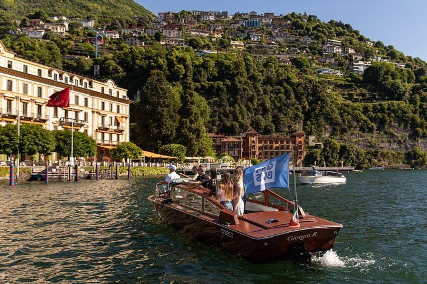 Un bateau nommé « Giorgio R » sur une eau calme, un drapeau rouge et un bâtiment sur une colline, également orné d’un drapeau rouge. 3