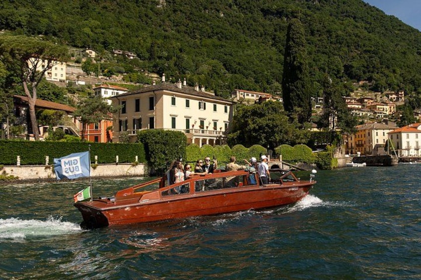 Un bateau rouge avec des passagers, naviguant sur un lac entouré de bâtiments et de verdure. 1