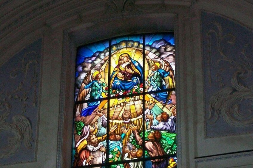 A stained glass window with religious figures and a haloed central figure. 4