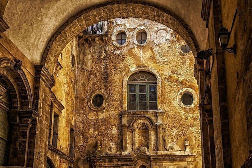 An arched doorway with a window, ornate stonework, and circular windows. 3