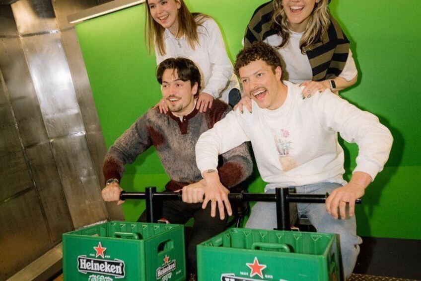 People in an elevator with green walls and Heineken crates. 2