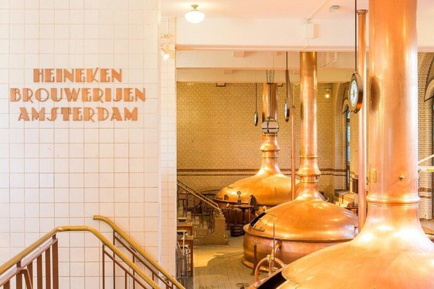 Interior de una cervecería con equipo de elaboración de cobre y un letrero que dice 'HEINEKEN BROUWERIJEN AMSTERDAM'. 2