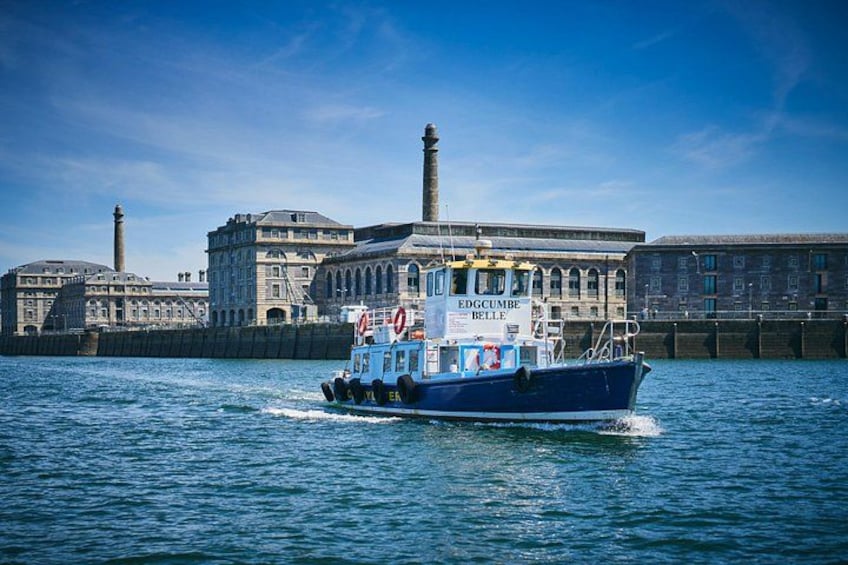 A blue boat named 'EDGUMBE BELLE' on water with a historic building and a lighthouse in the background. 4