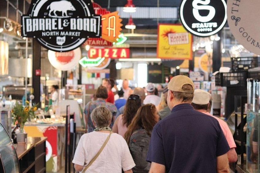 A busy indoor market with people walking, signs for 'Barrel & Bohr North Market' and 'Pizza', and various stalls. 3