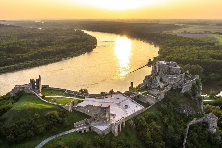 Vista aérea de un castillo histórico sobre un río al atardecer. 1
