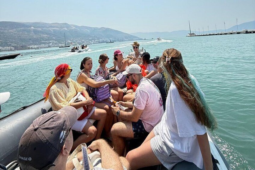 Un grupo de personas en un bote, con una masa de agua y tierra distante al fondo. 3