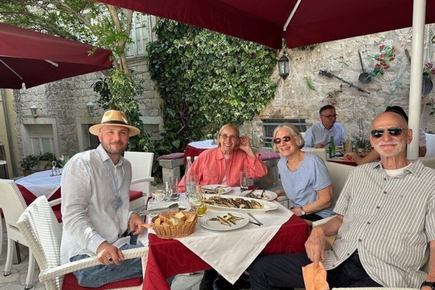 Un groupe de personnes est assis à une table à l’extérieur, où elles prennent un repas et boivent des boissons. 3