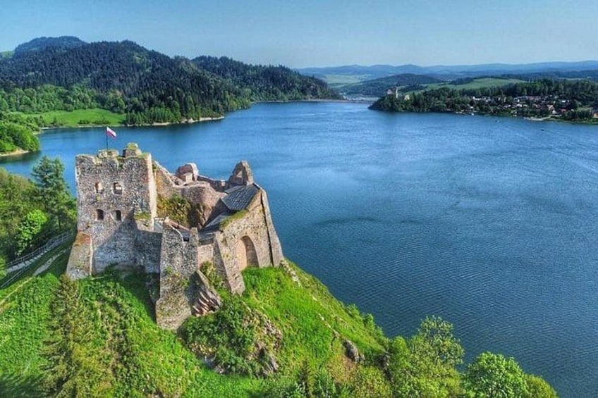 Un castello su un lago, circondato da vegetazione e colline sullo sfondo. 2
