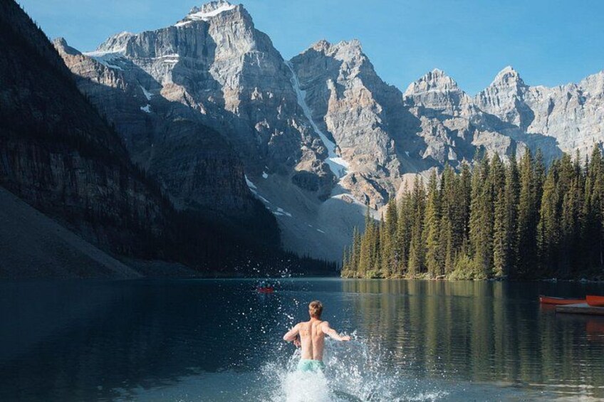 A person in a lake with mountains in the background. 3