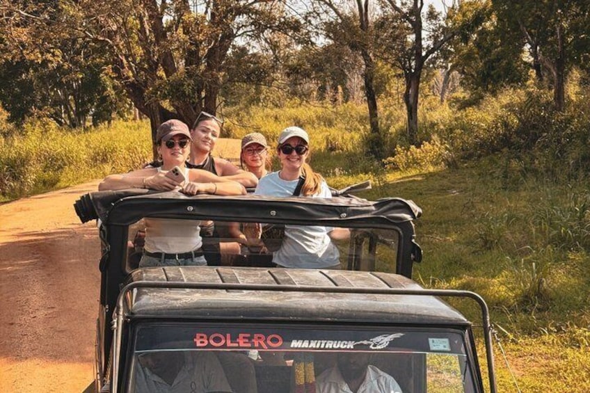 A Bolero Mantruck vehicle with four people on a rural road surrounded by trees. 5