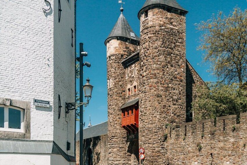 A historic stone tower with a red door, a white building with a sign, and a clear blue sky. 2