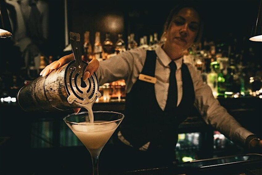 A bartender pouring a drink into a martini glass. 1