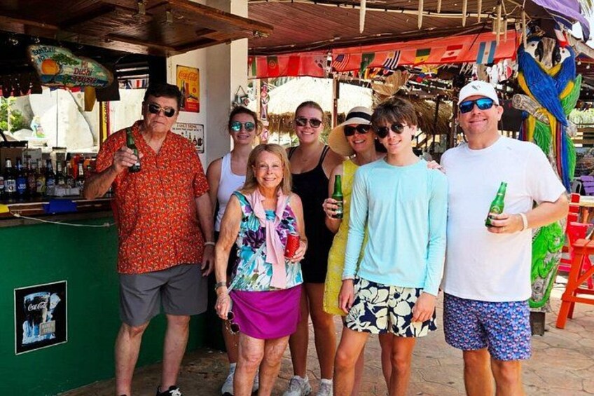 A group of people standing in front of a bar with a colorful parrot and various items on display. 5